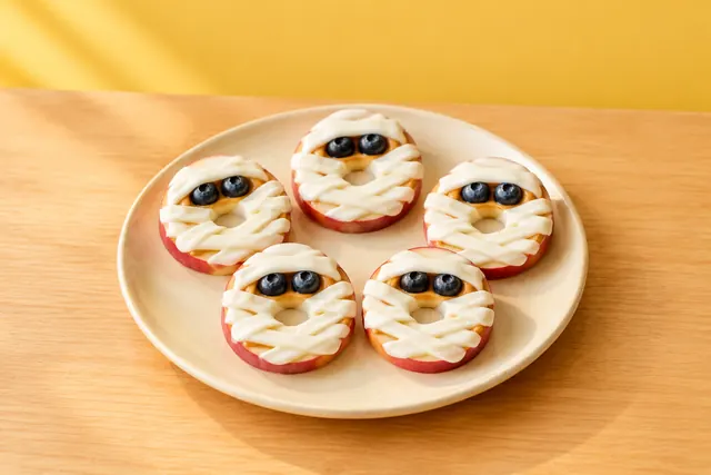 Apple rings wrapped in yogurt bandages with blueberry eyes, like mummies